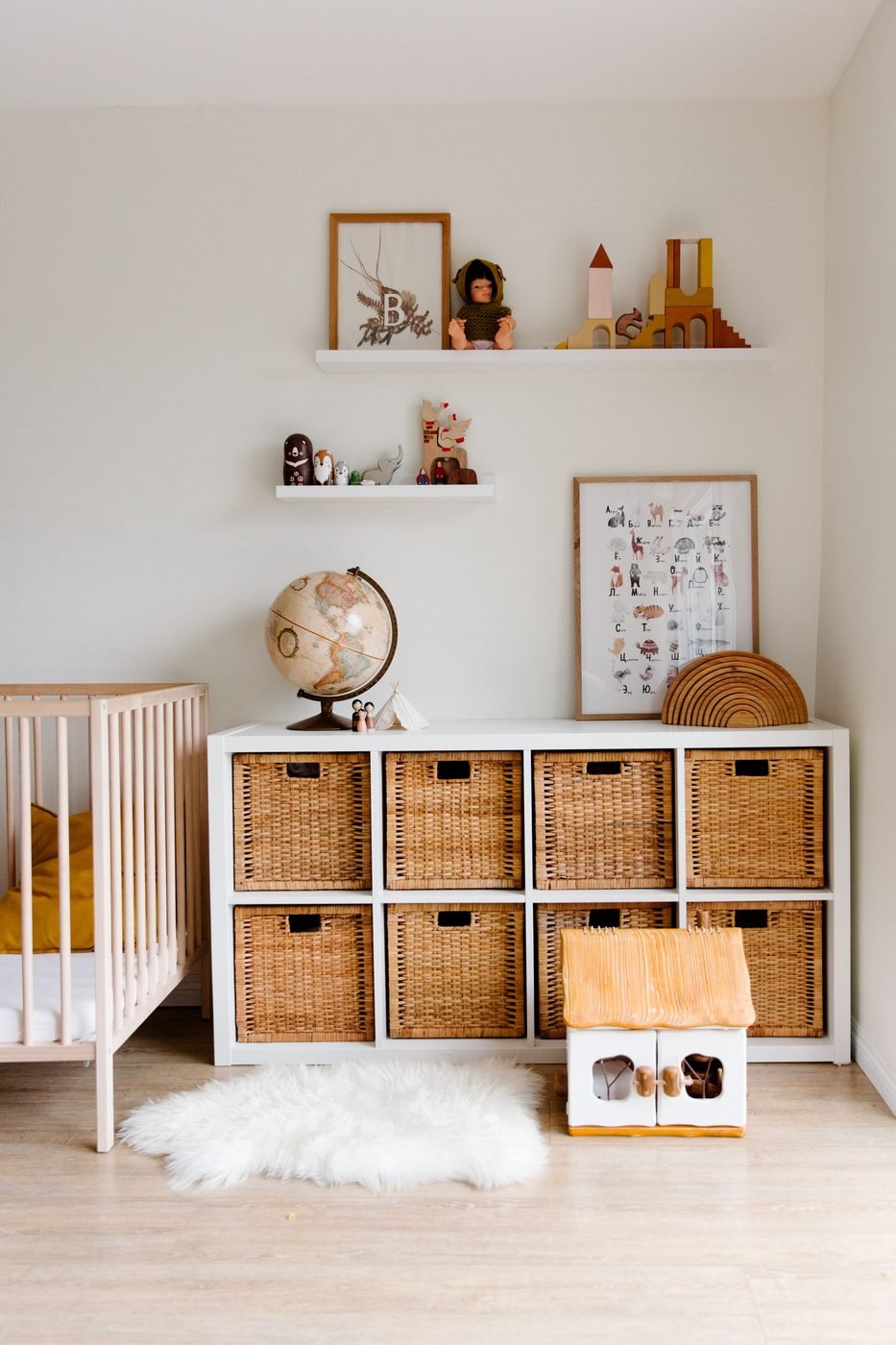 Habitación infantil con un mueble de cubos con cestas de fibra, una cuna y estantes con juguetes.
